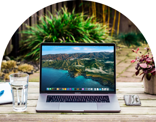 Laptop on outdoor table with greenery in background, representing remote work and reduced carbon emissions and corporate sustainability
